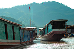 Wycieczka do Laosu:  charakterystyczne długie łodzie pływającej po Mekongu